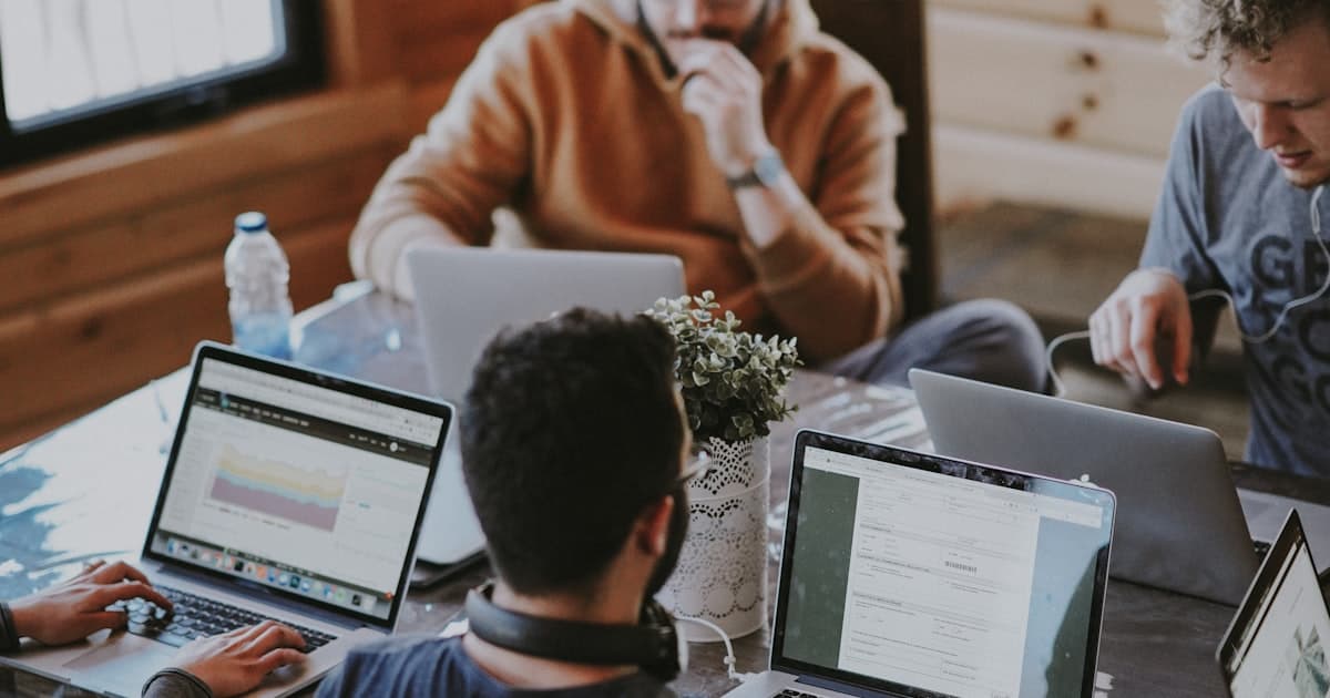 Team of IT professionals collaborating on laptops during a staffing review meeting
